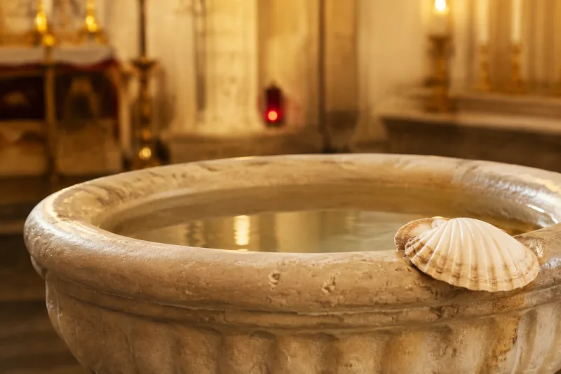 Clear water and a scallop shell in a stone baptismal font