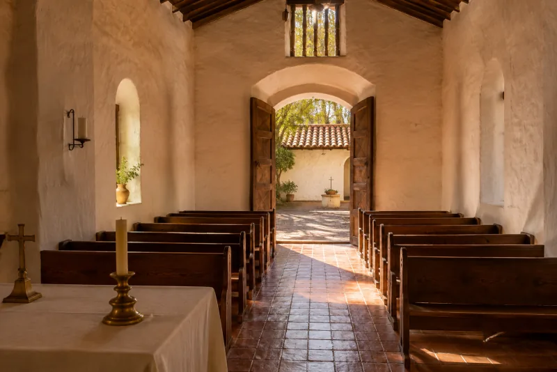 La luz del sol ilumina los bancos de una capilla sencilla y su puerta abierta al patio.